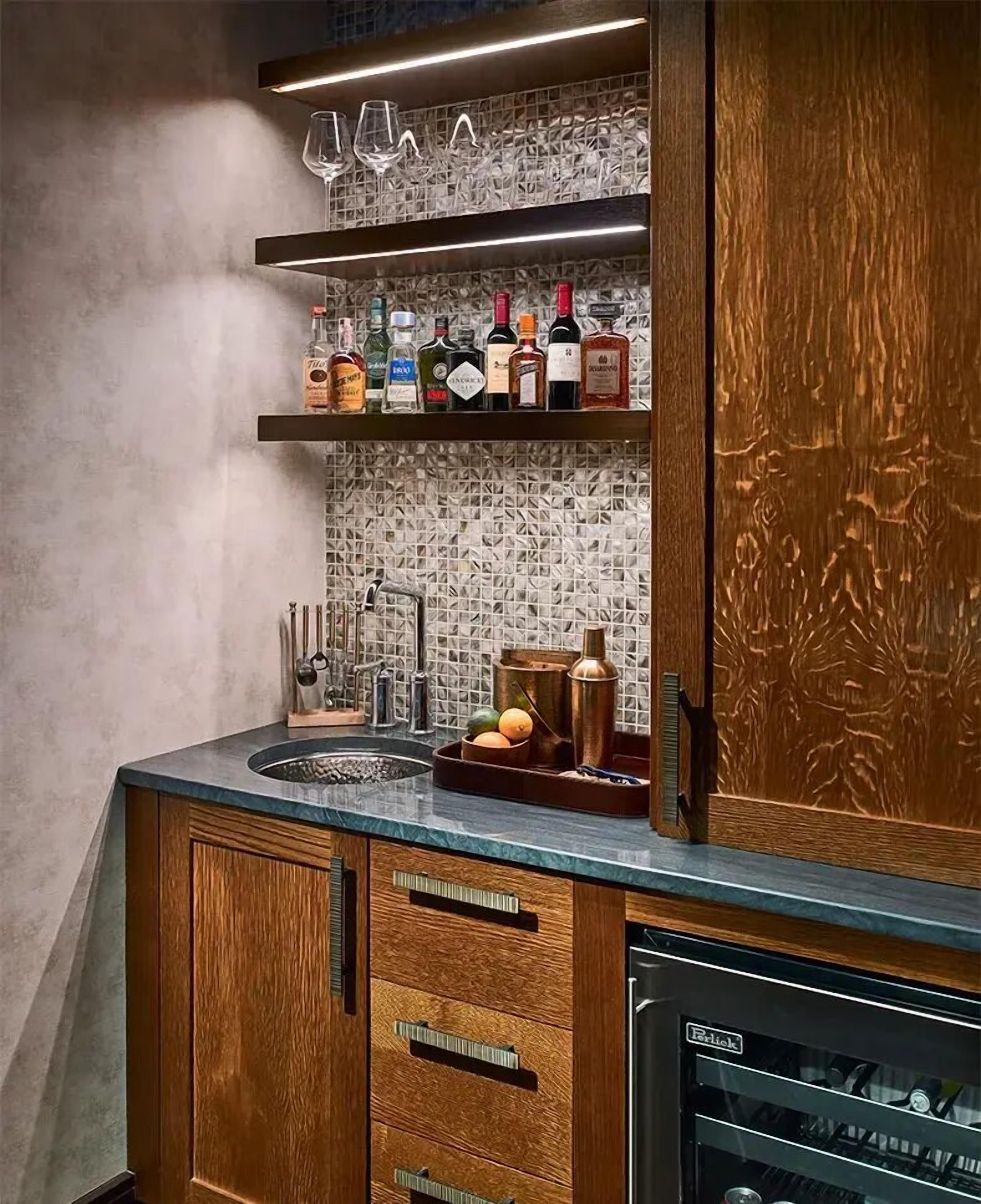 Una cocina con armarios de madera, un lavabo y una botellera con botellas.