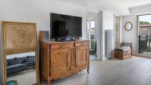 Een woonkamer met een grote televisie op een houten kast, een bank en een grote spiegel.