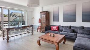 Een moderne woonkamer met een eethoek, grote ramen en uitzicht naar buiten.