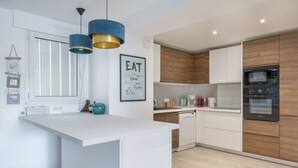Een moderne keuken met een centraal eiland, houten kastjes en roestvrijstalen apparatuur.