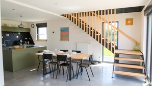 Cozinha moderna com área de jantar, escada e vista para o verde lá fora.