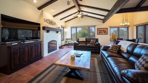 A spacious living room with a fireplace, leather sofa, and a television. - Stunning 3 bed/2.5 bath Mediterranean Villa with FABULOUS Ocean Views! (Cambria)