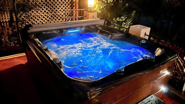 Un bain à remous avec une terrasse en bois et une clôture en treillis en arrière-plan.