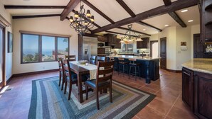 A spacious kitchen with dark wooden beams, a large island, and a dining area with a view. - Stunning 3 bed/2.5 bath Mediterranean Villa with FABULOUS Ocean Views! (Cambria)