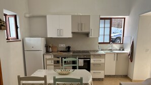 A compact kitchen with a dining area, featuring a refrigerator, stove, sink, and cabinets.
