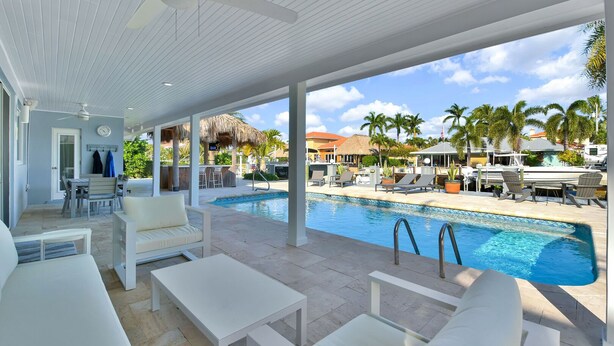 A poolside area with a covered seating area, a bar, and a view of the pool and surrounding landscape. - 943 Managed by Brampton Park (Delray Beach)