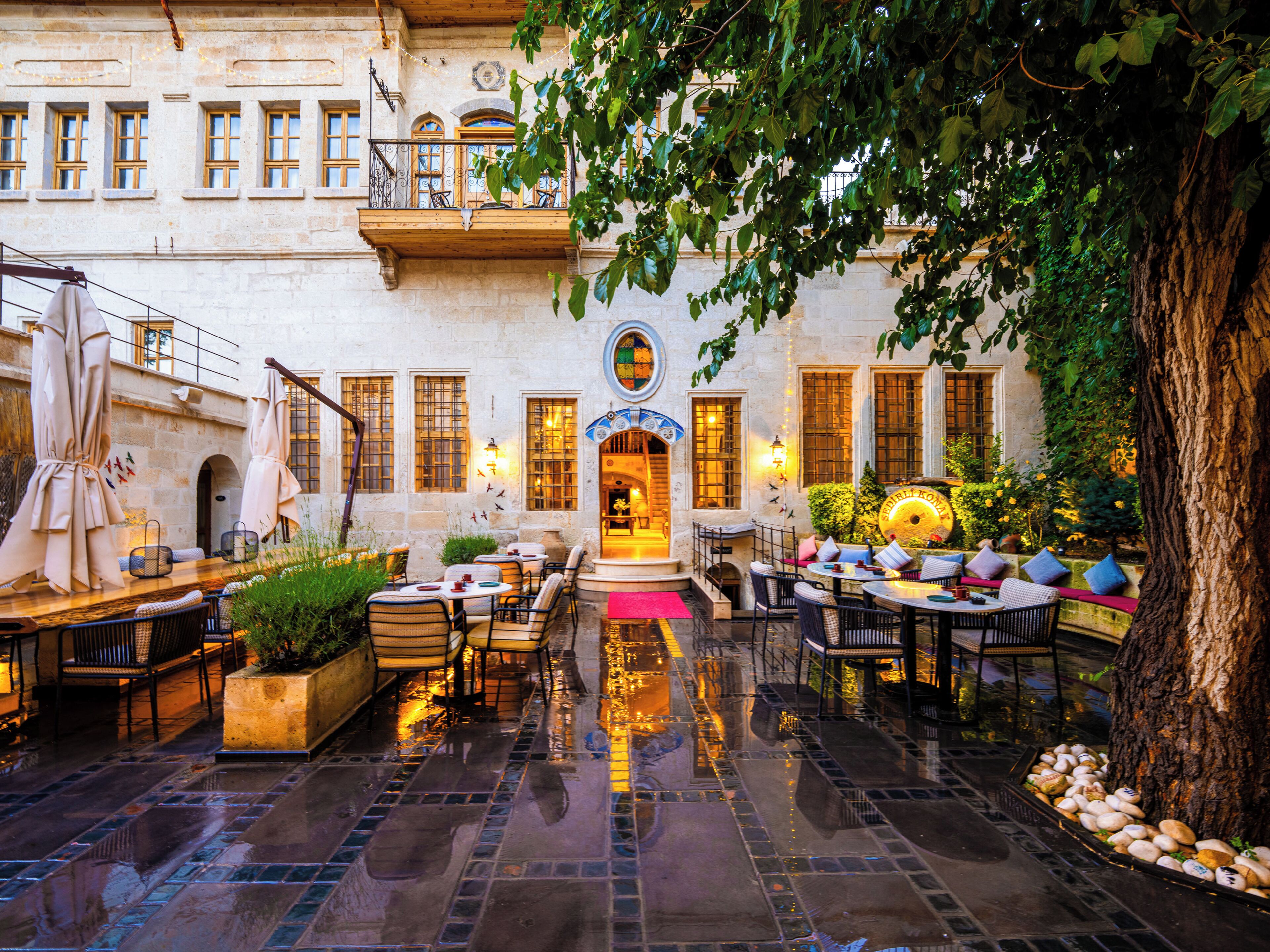 A courtyard with outdoor seating, a fountain, and a building with multiple windows and balconies.