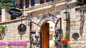 A stone building with a sign for 'Sedirli Konak Hotel,' an entrance with an ornate wooden door, and flower planters outside. - Sedirli Konak 1751 - Special Class (Ürgüp)