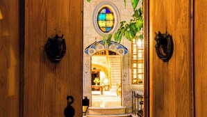 A wooden door leading to a room with a red carpet, a stained glass window, and a small balcony with a plant. - Sedirli Konak 1751 - Special Class (Ürgüp)