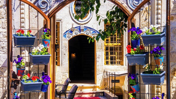 An outdoor seating area with chairs and a red rug, surrounded by potted plants and a decorative archway. - Sedirli Konak 1751 - Special Class (Ürgüp)