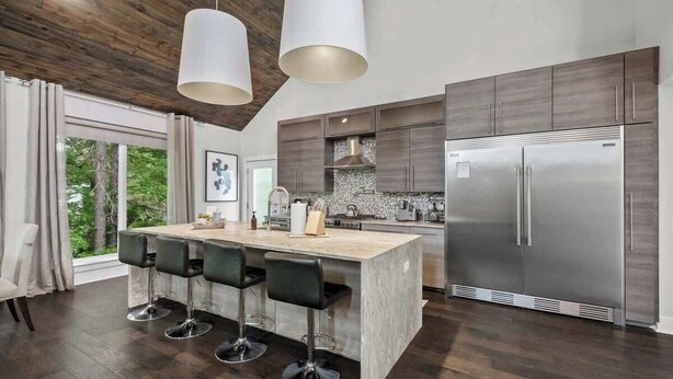 A modern kitchen with a central island, bar stools, stainless steel appliances, and a view of the outdoors. - Fayetteview Rooftop Balcony Hot Tub 5 Min to DT (Fayetteville)
