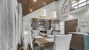 A modern kitchen with dark cabinets, a stainless steel refrigerator, and pendant lighting. - Fayetteview Rooftop Balcony Hot Tub 5 Min to DT (Fayetteville)