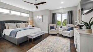 A bedroom with a bed, a desk, two chairs, a ceiling fan, and a large window. - Fayetteview Rooftop Balcony Hot Tub 5 Min to DT (Fayetteville)