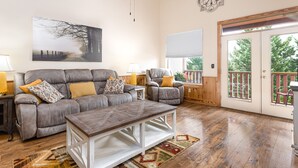 A living room with a gray sofa, two armchairs, a wooden coffee table, and a large painting on the wall.