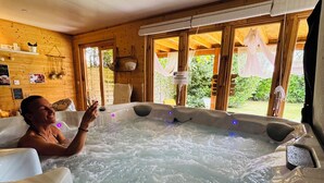 Une personne se détend dans un bain à remous, avec vue sur la verdure environnante.