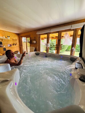 Une personne se détend dans un bain à remous, avec vue sur la verdure environnante.