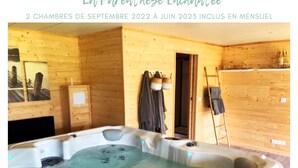 Une salle de spa avec un jacuzzi, des murs en bois et des serviettes suspendues à des crochets.
