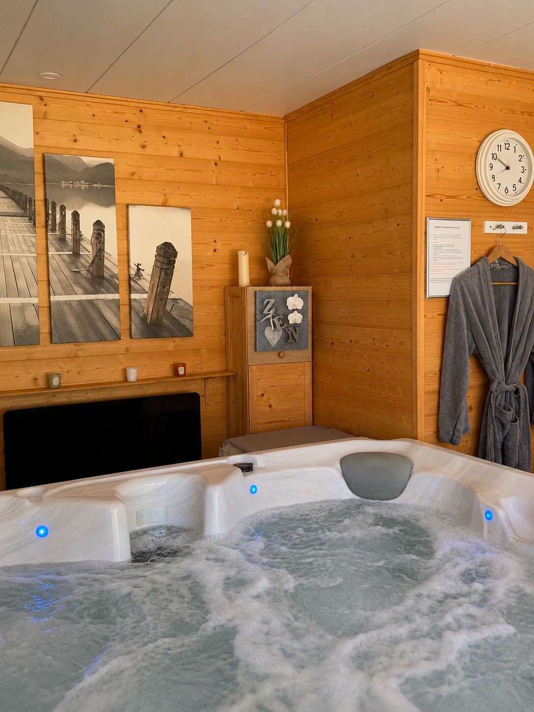 Un spa con sala de madera, tinaco caliente, paredes de madera y un reloj.