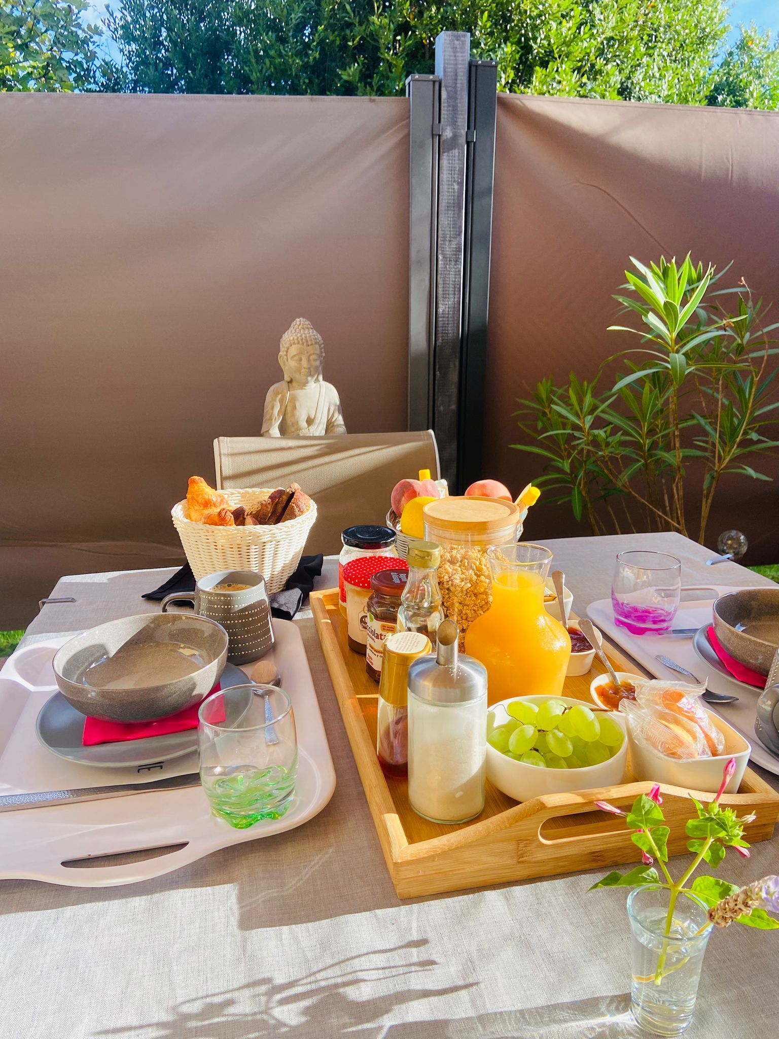 Morgenmad med en Buddha-figur, en bakke med mad og et glas appelsinjuice.