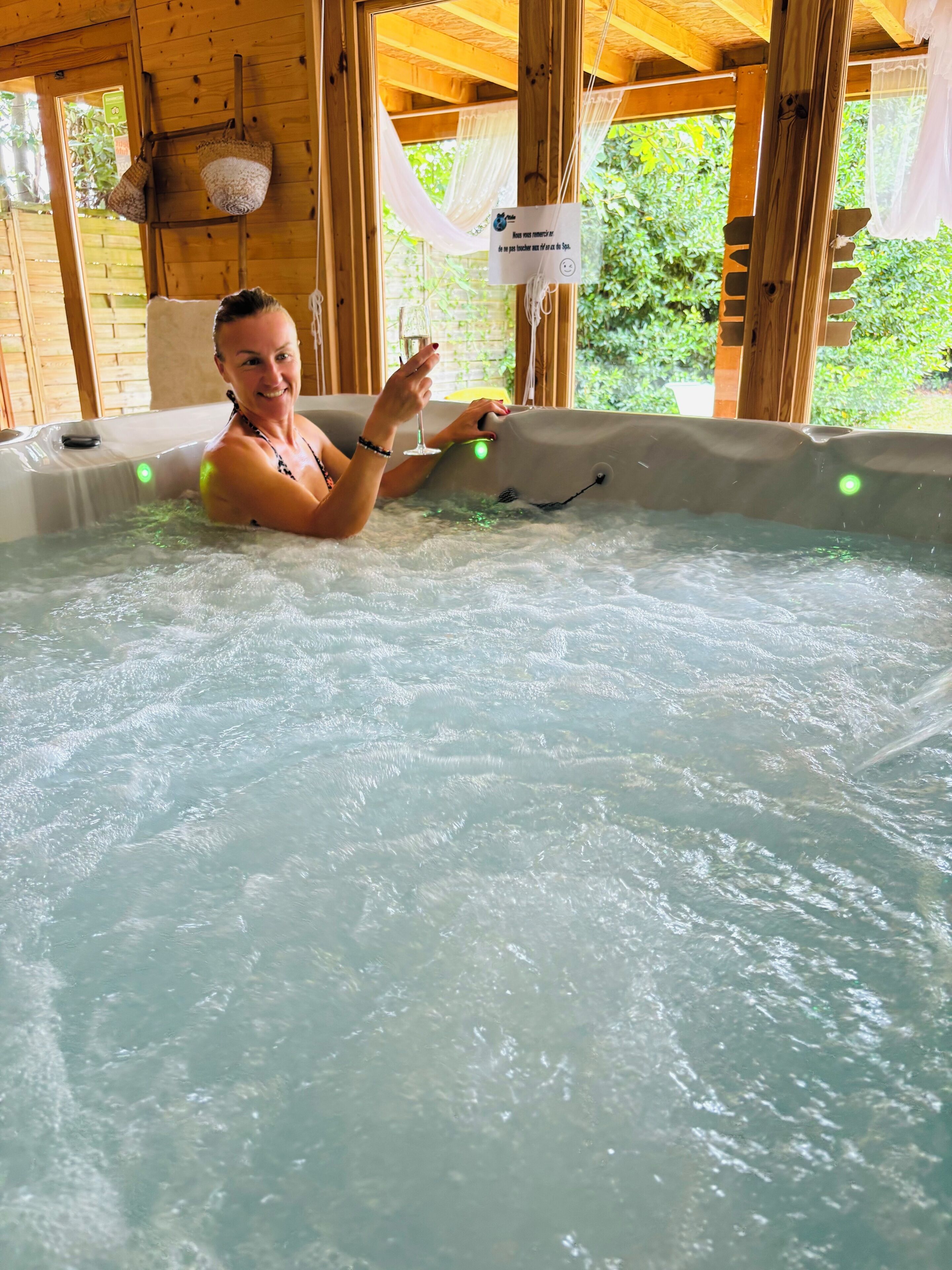 A person in a hot tub with wooden beams and a sign in the background.
