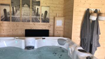 Habitación de cabaña de madera con un jacuzzi, paredes de madera y tres cuadros con imágenes de un puente.