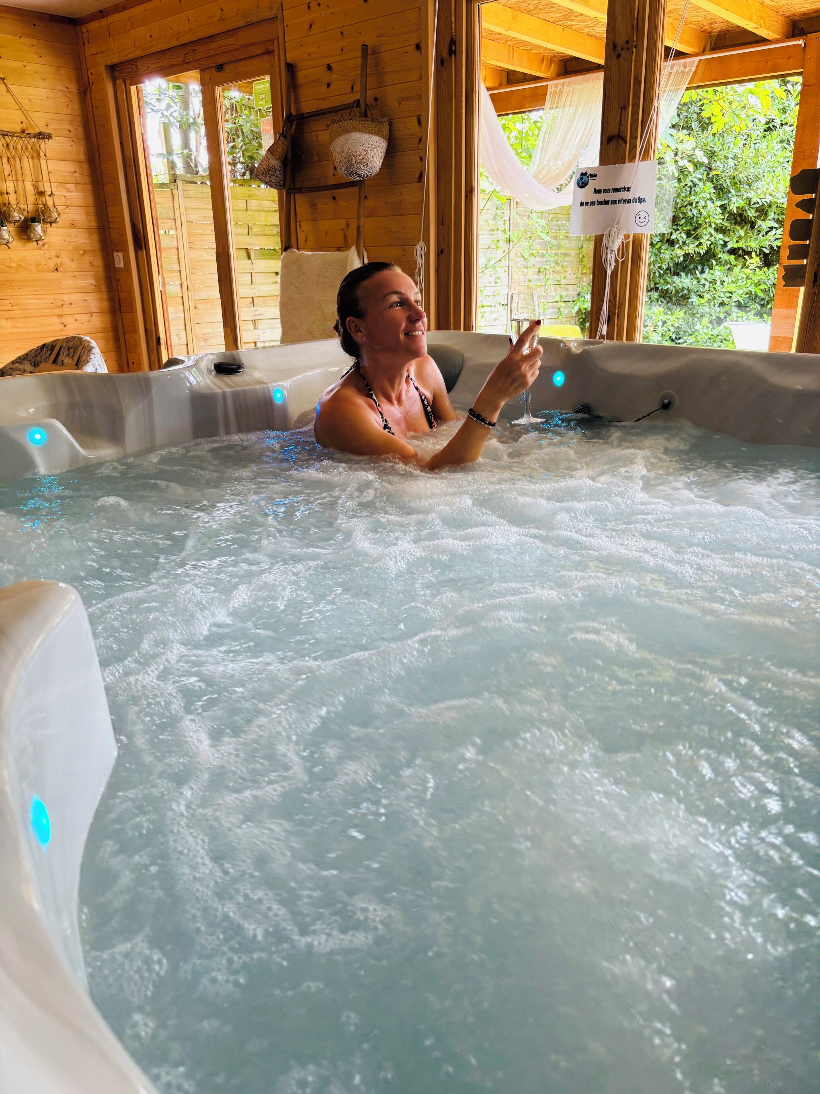 Eine Person in einem Whirlpool mit Holzwänden und einem Fenster.
