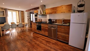 A modern kitchen with wooden cabinets, stainless steel appliances, and a dining area with a table and chairs.