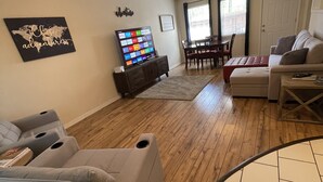 A living room with a grey sofa, a TV, a ceiling fan, and a world map artwork on the wall. - Cute Townhouse in Cherokee Village where adventures await! (Cherokee Village)