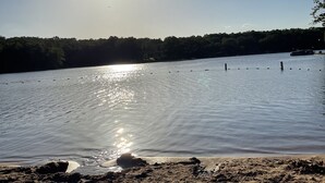 A sandy beach with a calm lake, a clear sky, and a boat in the distance. - Cute Townhouse in Cherokee Village where adventures await! (Cherokee Village)