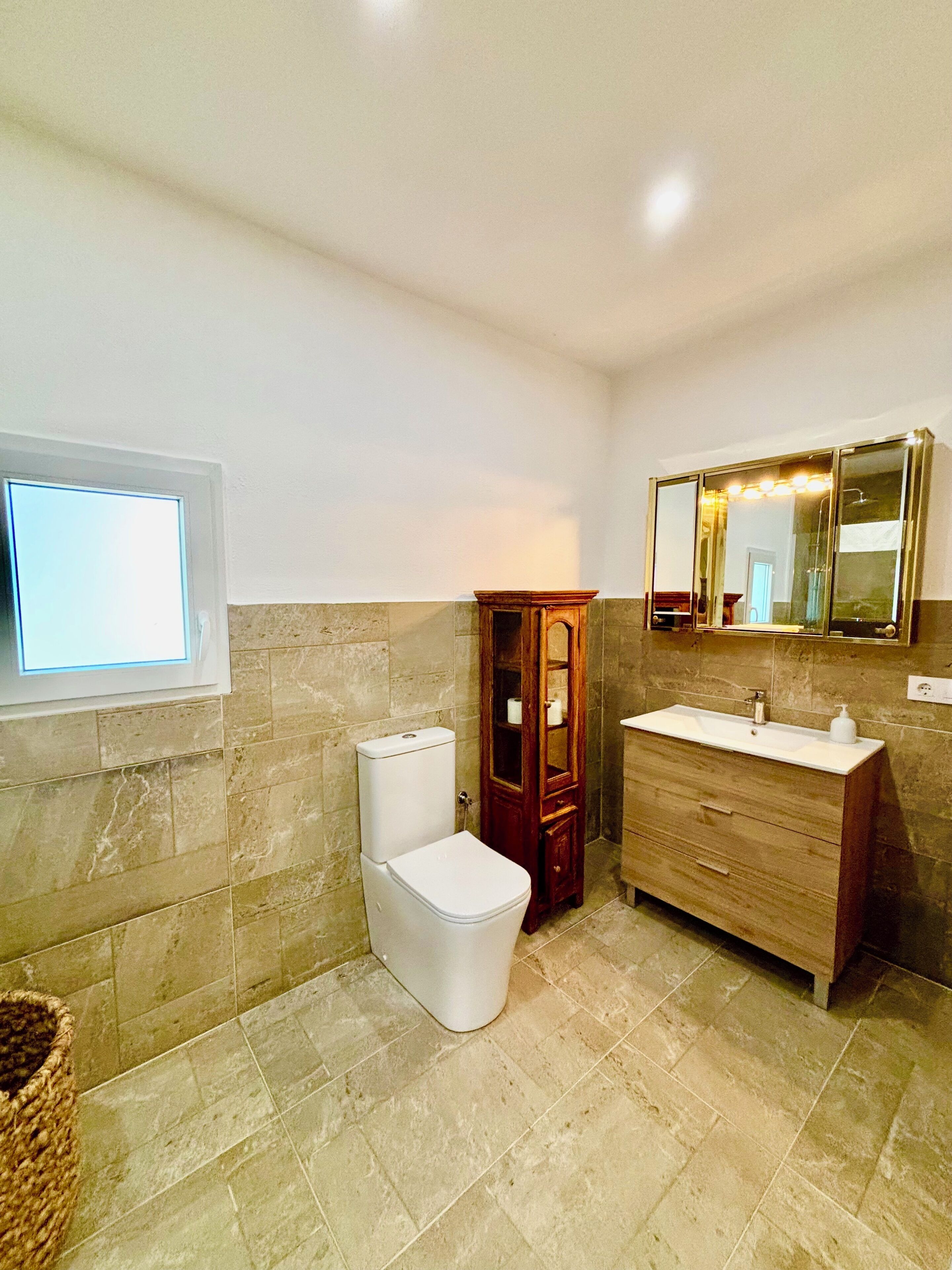 Un baño con inodoro, tocador y un espejo grande.
