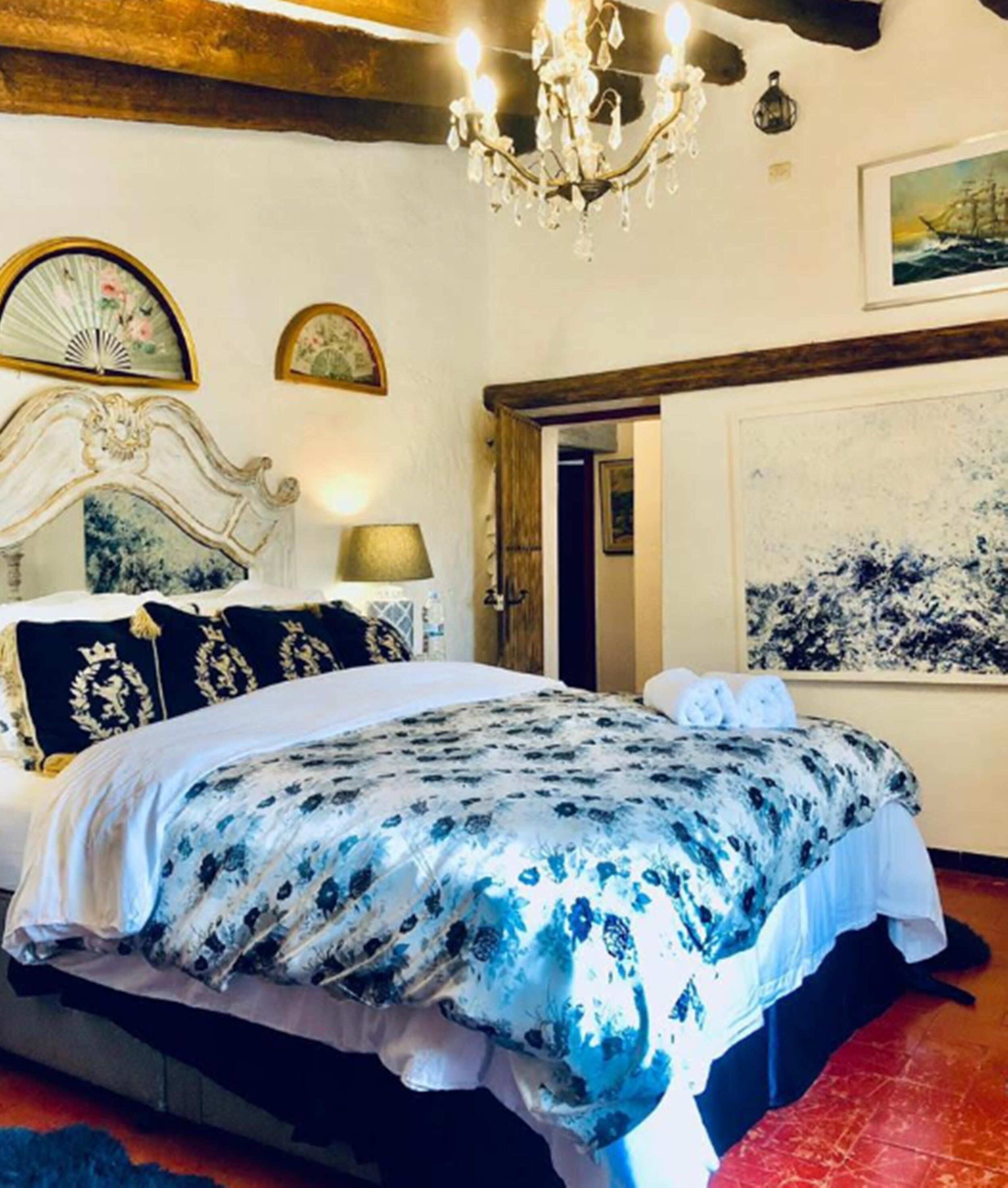 Un dormitorio con cama, una araña, un cuadro y un reloj en la pared.