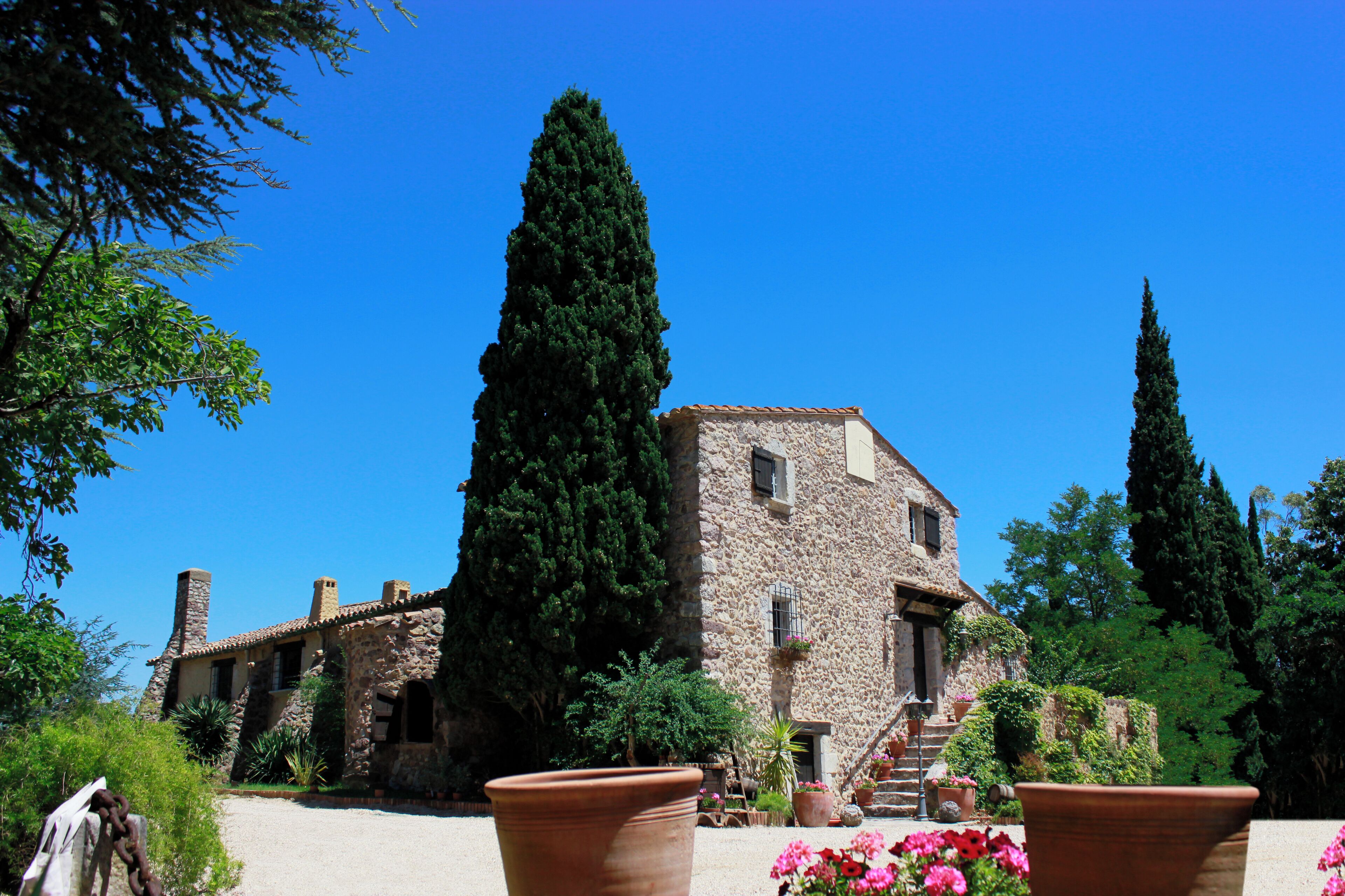 Un edificio in pietra con tetto in tegole, immerso nel verde e decorato con piante in vaso.