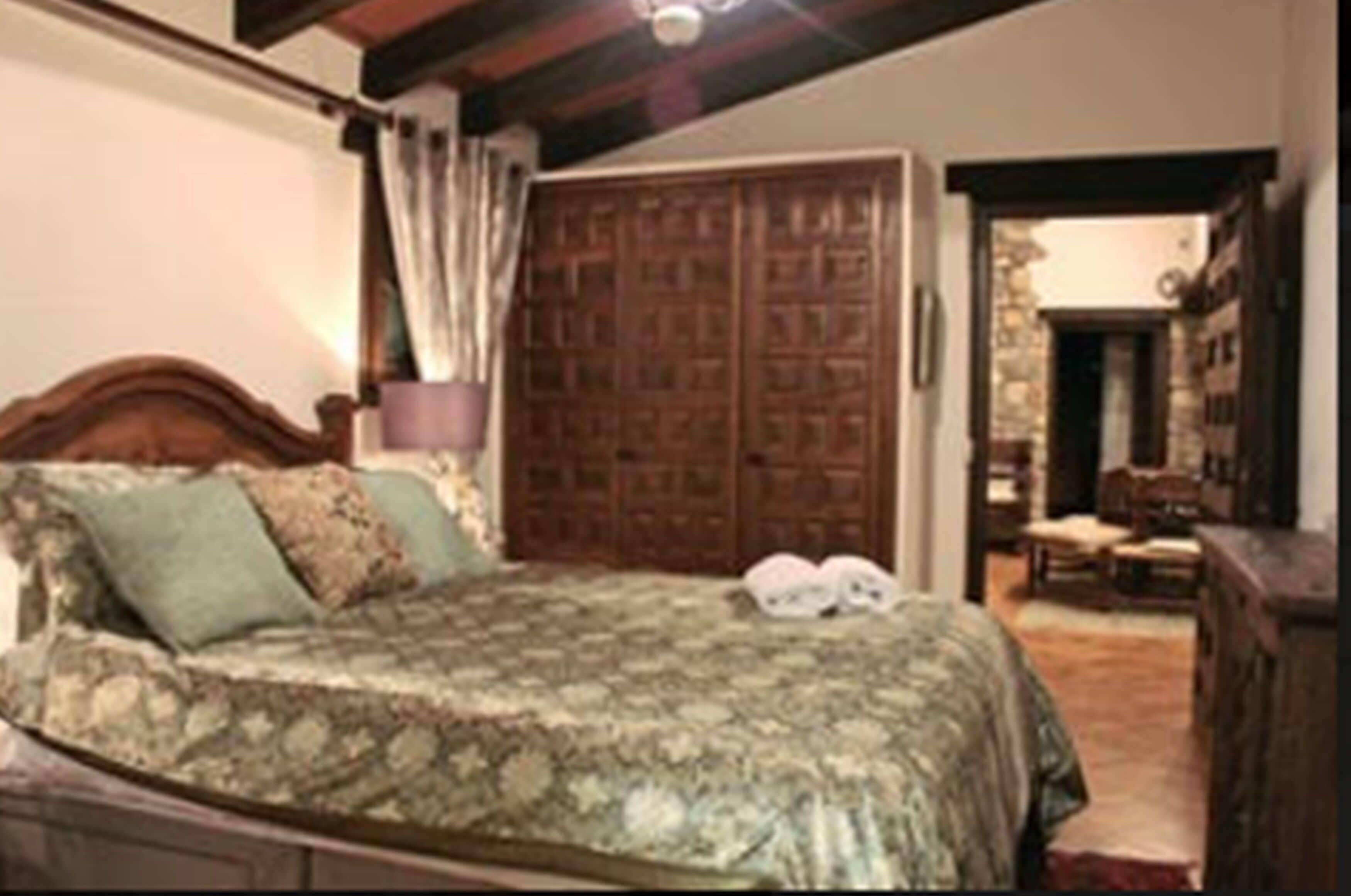 Un dormitorio con una cama de madera, un armario amplio y una mesita de noche con una lámpara.