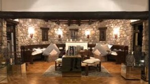 A stone-walled lounge area with a fireplace, wooden furniture, and stone flooring. - Masia Mimosa (Darnius)