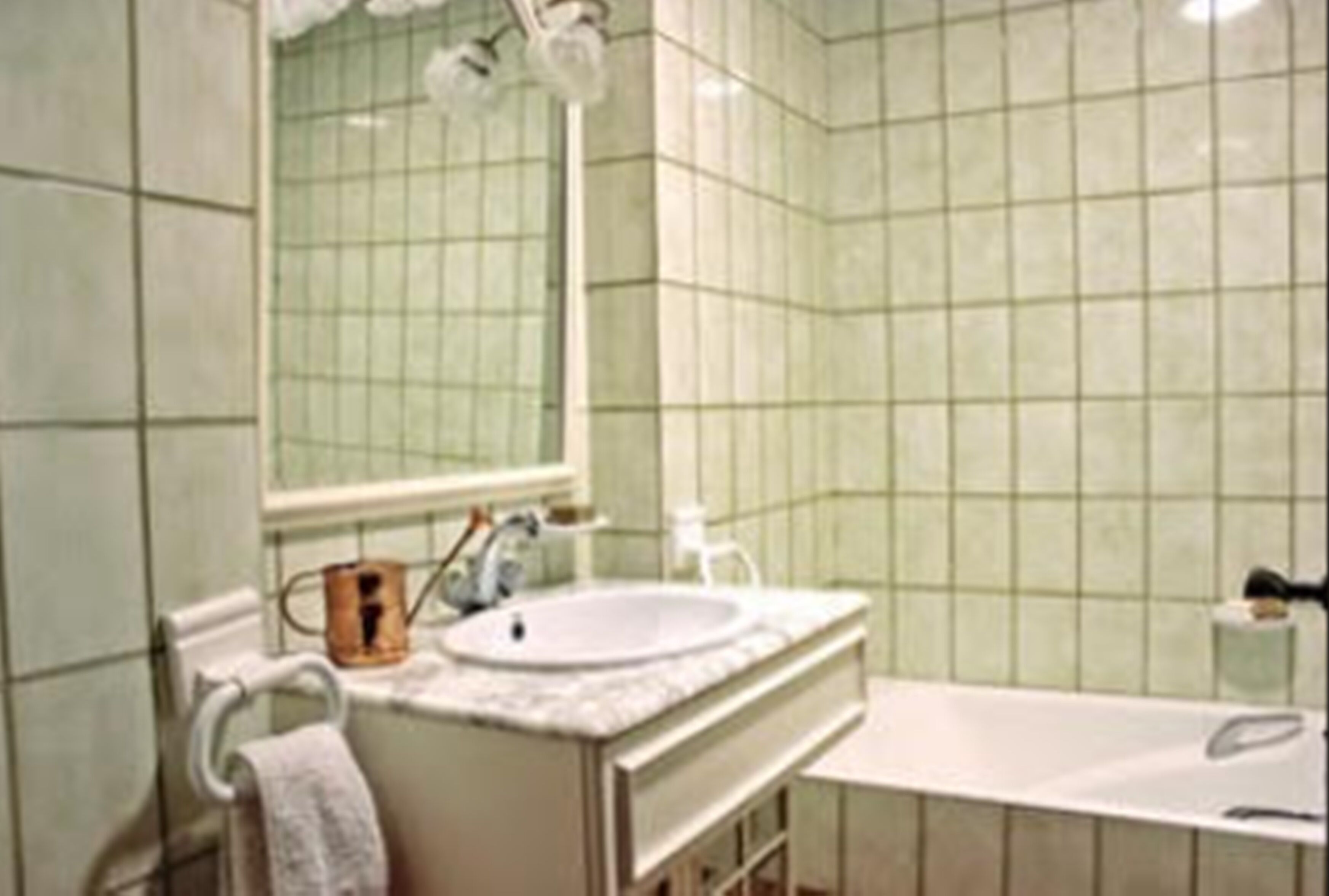 Un baño con lavamanos, espejo y bañera.