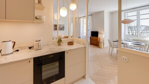A modern kitchen with a marble countertop, built-in oven, and a dining area with a view of the city.