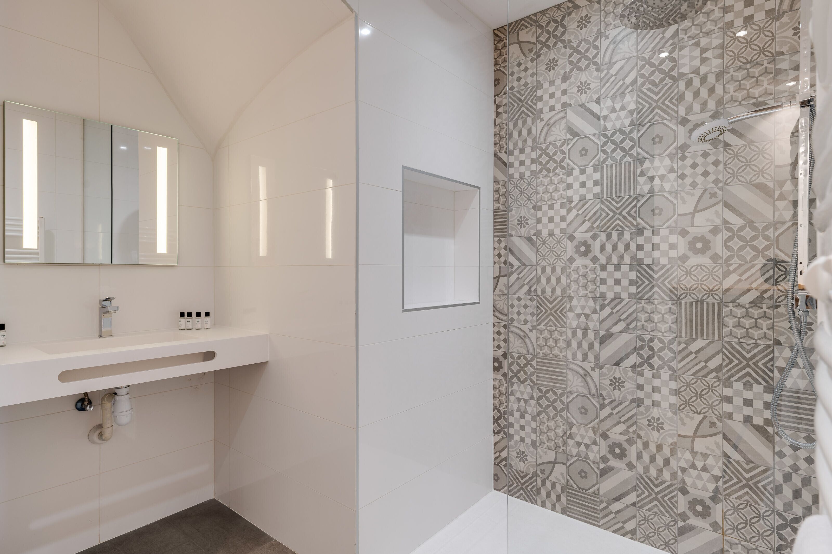 Casa de banho moderna com um espelho grande, lavatório e chuveiro com azulejos estampados.