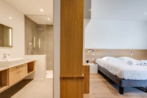 Une salle de bain moderne avec un grand miroir, une douche et un mur d’accent en bois.
