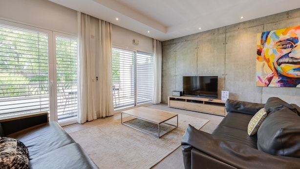 A modern living room with a large TV, a sofa, and a painting on the wall.