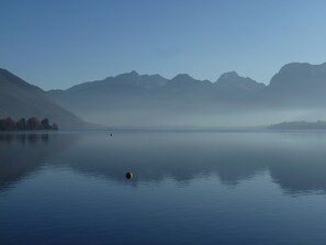 Un lac paisible, avec des montagnes en arrière-plan et un seul bateau sur l’eau.