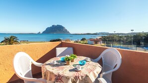 En balkon med et bord dækket til to, der kigger ud over kysten med en markant klippeformation.