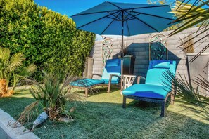 A patio area with a large umbrella, wicker chairs, and a small table.