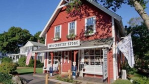 Un edificio rojo con el letrero "1856 Country Store", un porche y una bandera.