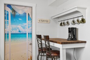 Eine Küche mit einer Kaffeestation, einem Holztisch und Stühlen.