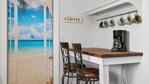 Una cocina con estación de café, una mesa de madera y sillas.
