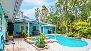 A pool area with a patio, seating, and tropical plants. - Pool Party South · 3BR · Pool & Spa · Updated Jan 2025 (Holmes Beach)