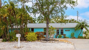 A turquoise building with a sign reading "Pool Party Suite." - Pool Party South · 3BR · Pool & Spa · Updated Jan 2025 (Holmes Beach)