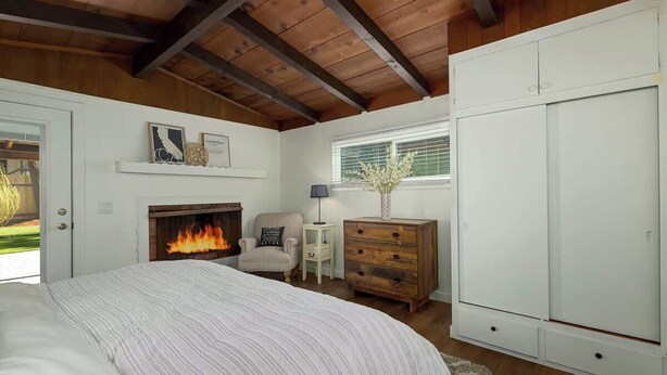 A bedroom with a bed, a fireplace, a dresser, and a wardrobe.