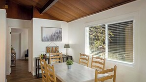 A dining area with a table, chairs, a lamp, and a window with blinds.
