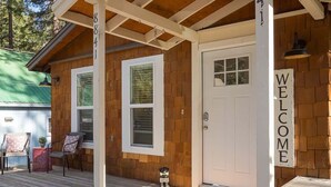 A wooden cabin with a porch, a welcome sign, and a door.